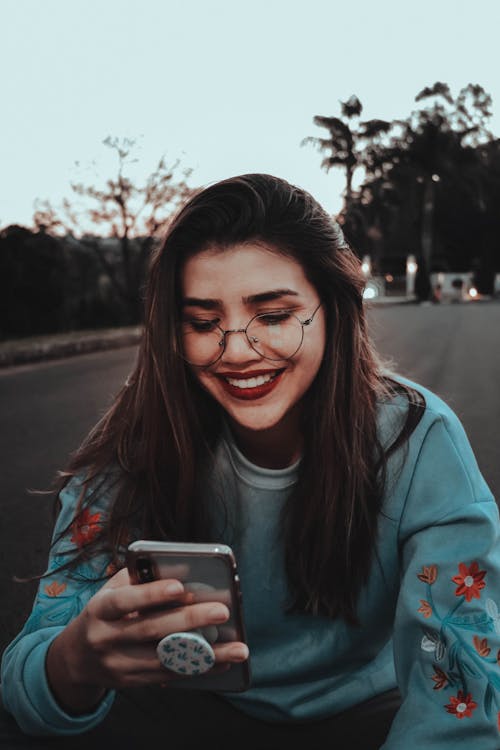 Woman smiling while checking her phone - representing partner checking recurring commission earnings